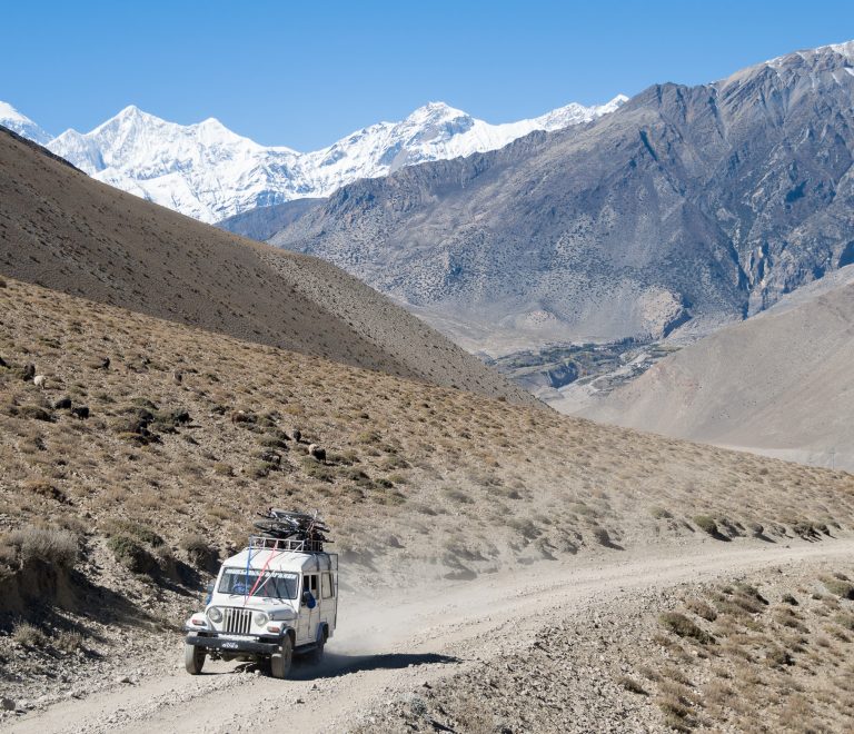 4WD jeep driving through rugged trails of Upper Mustang Nepal with barren landscapes, cliffs, and mountain views